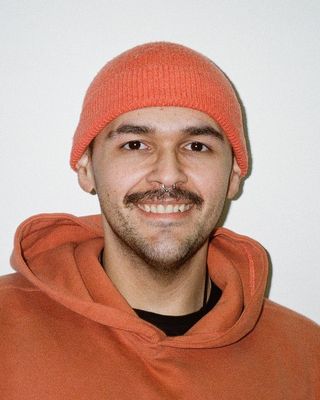 Retrato de Gabriel Sánchez Micó sonriendo, con gorro y sudadera naranjas